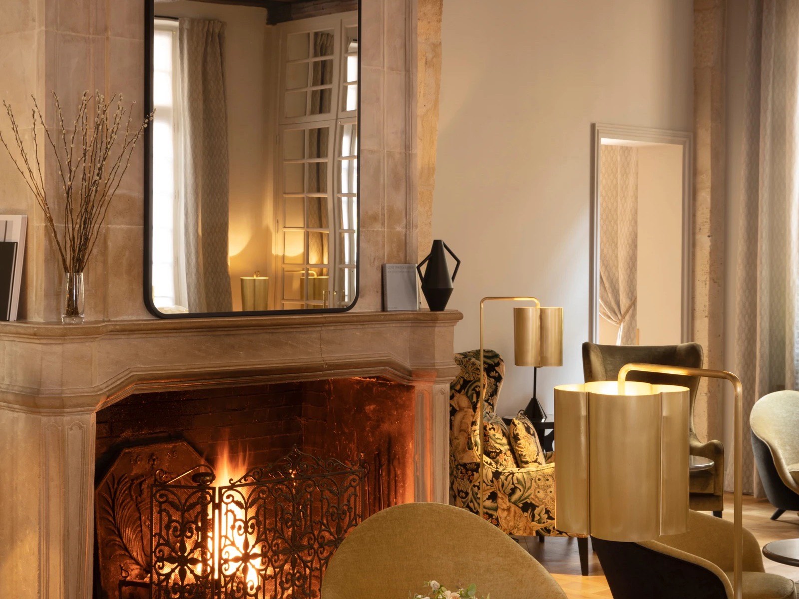 Salon de l'Hôtel d'Aubusson avec cheminée en pierre allumée et poutres apparentes