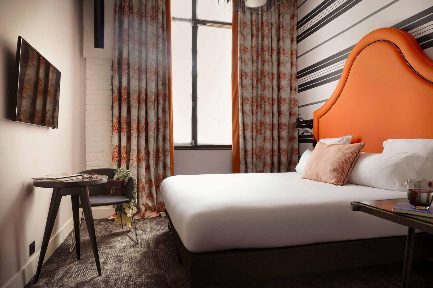 Une chambre de l'Hôtel Fabric, tête de lit orange et papier peint rayé