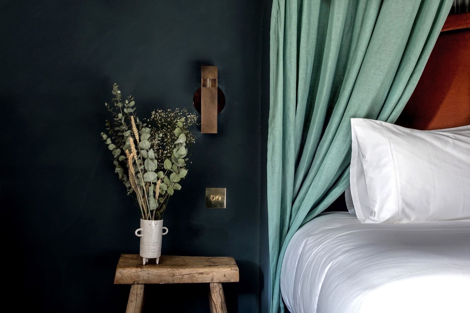 Chevet en bois brut et rideau de lin vert dans une chambre de l'Hôtel des Grands Boulevards, Paris 2e