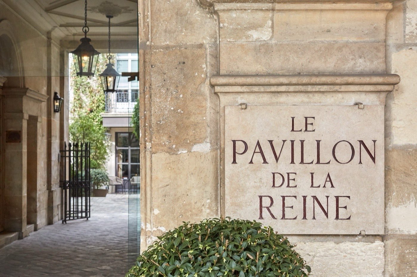 Entrée en pierre gravée du Pavillon de la Reine et passage vers sa cour, place des Vosges à Paris