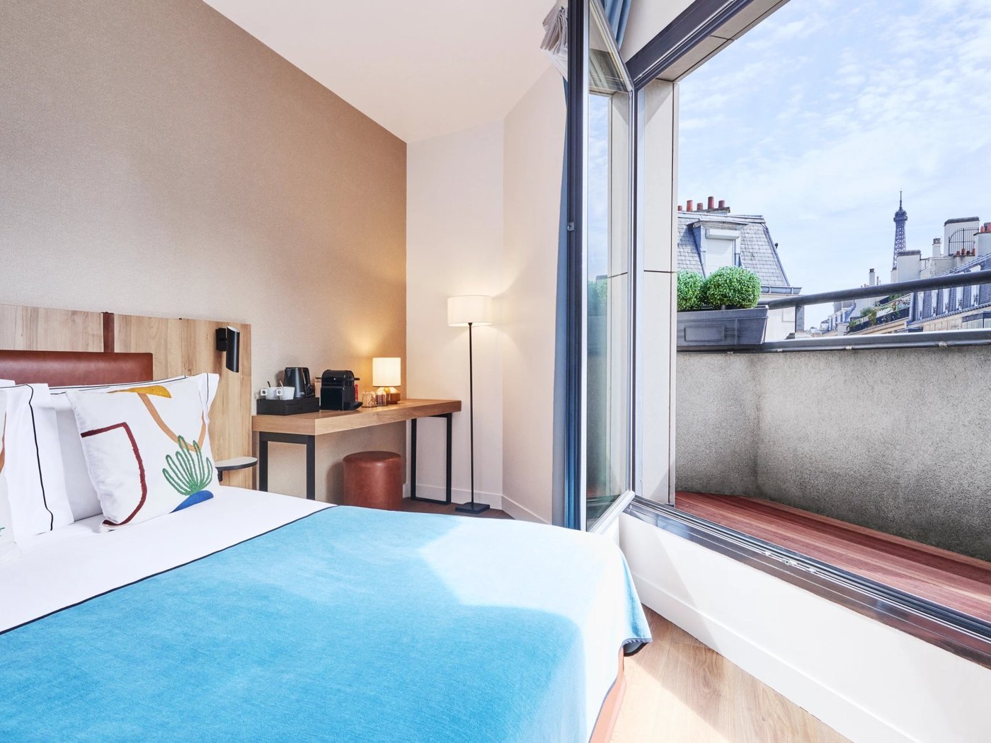 Une chambre à balcon du Plaza Tour Eiffel, le haut de la tour Eiffel visible au-dessus des toits