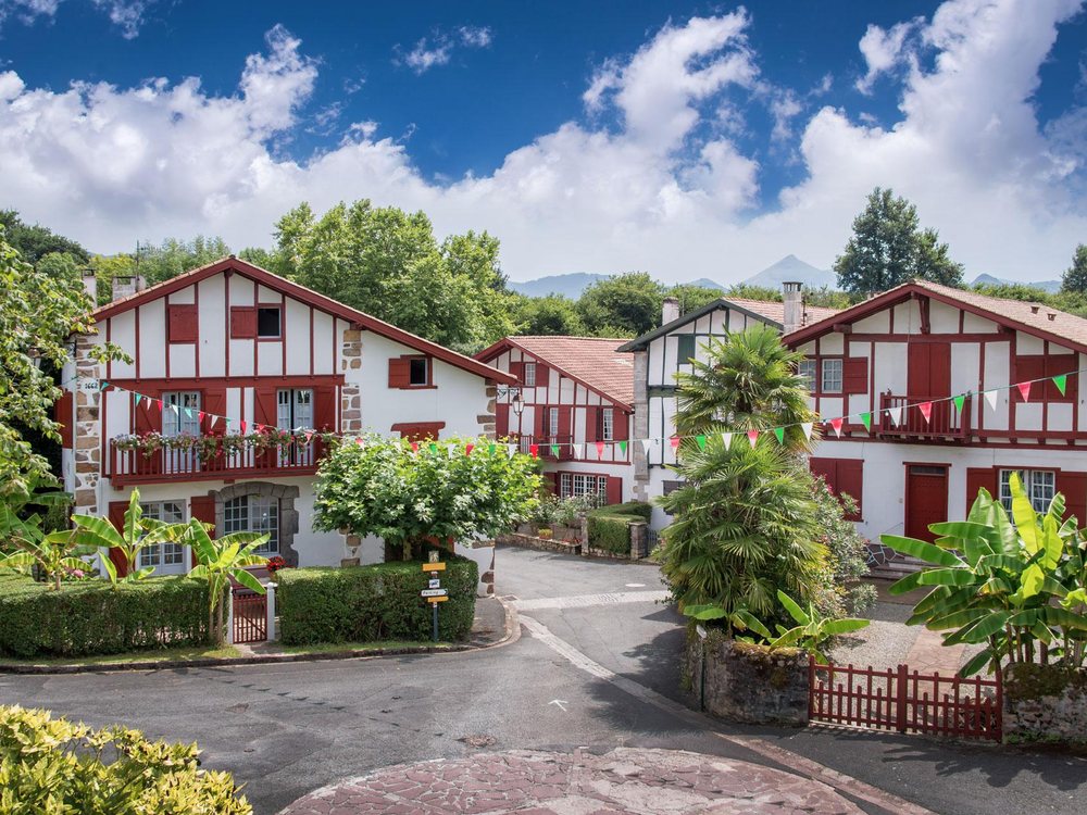 Les maisons basques blanches et rouges de l'Hôtel Indarra, à Arbonne, entourées de jardins et de palmiers