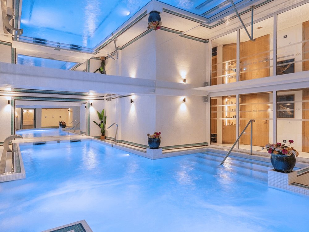 La piscine intérieure chauffée du spa Nuxe du Grand Tonic, éclairée en bleu sous une verrière