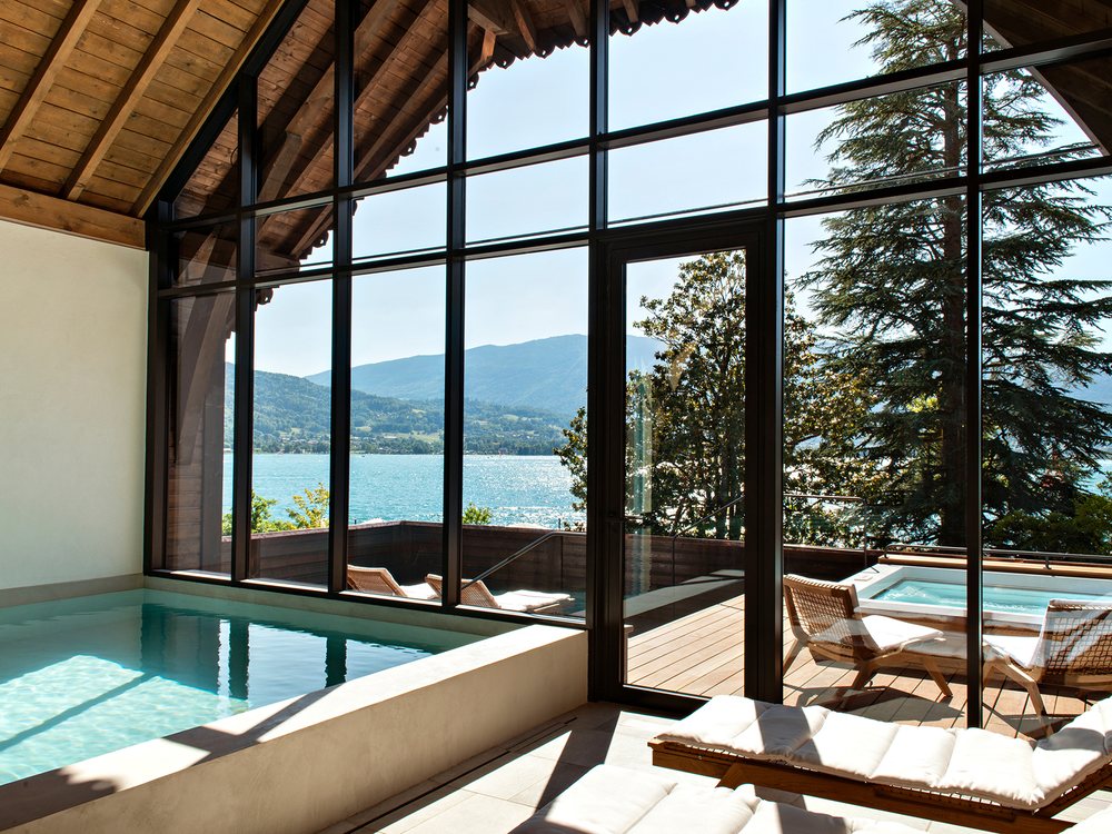 Le bord de la piscine intérieure de l'Auberge du Père Bise et le bain nordique sur la terrasse, face au lac d'Annecy