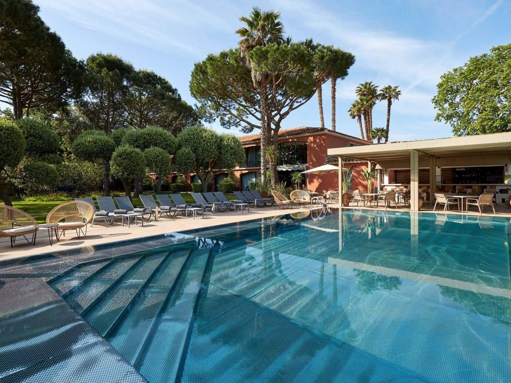 La piscine miroir de La Villa Duflot à Perpignan, bordée de pins parasols et d'oliviers taillés