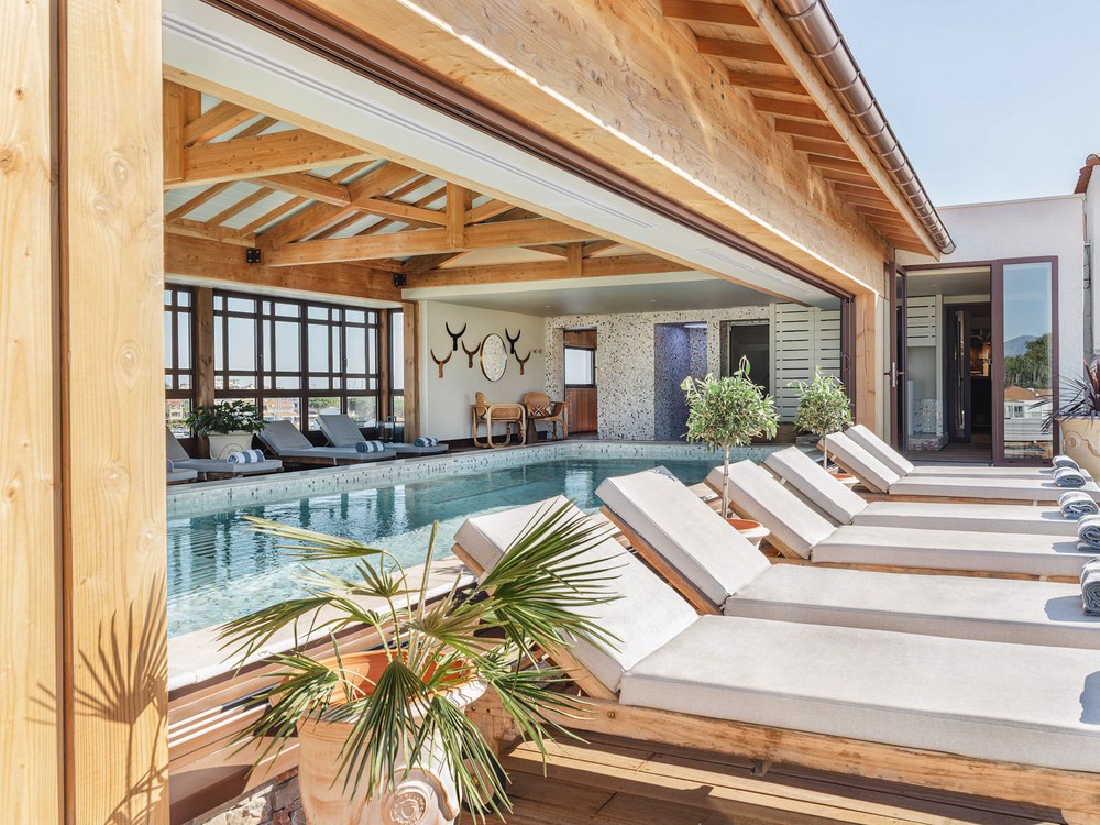 Le bassin chauffé du spa marin de l'Île de la Lagune, transats alignés sous une charpente de bois ouverte sur l'extérieur