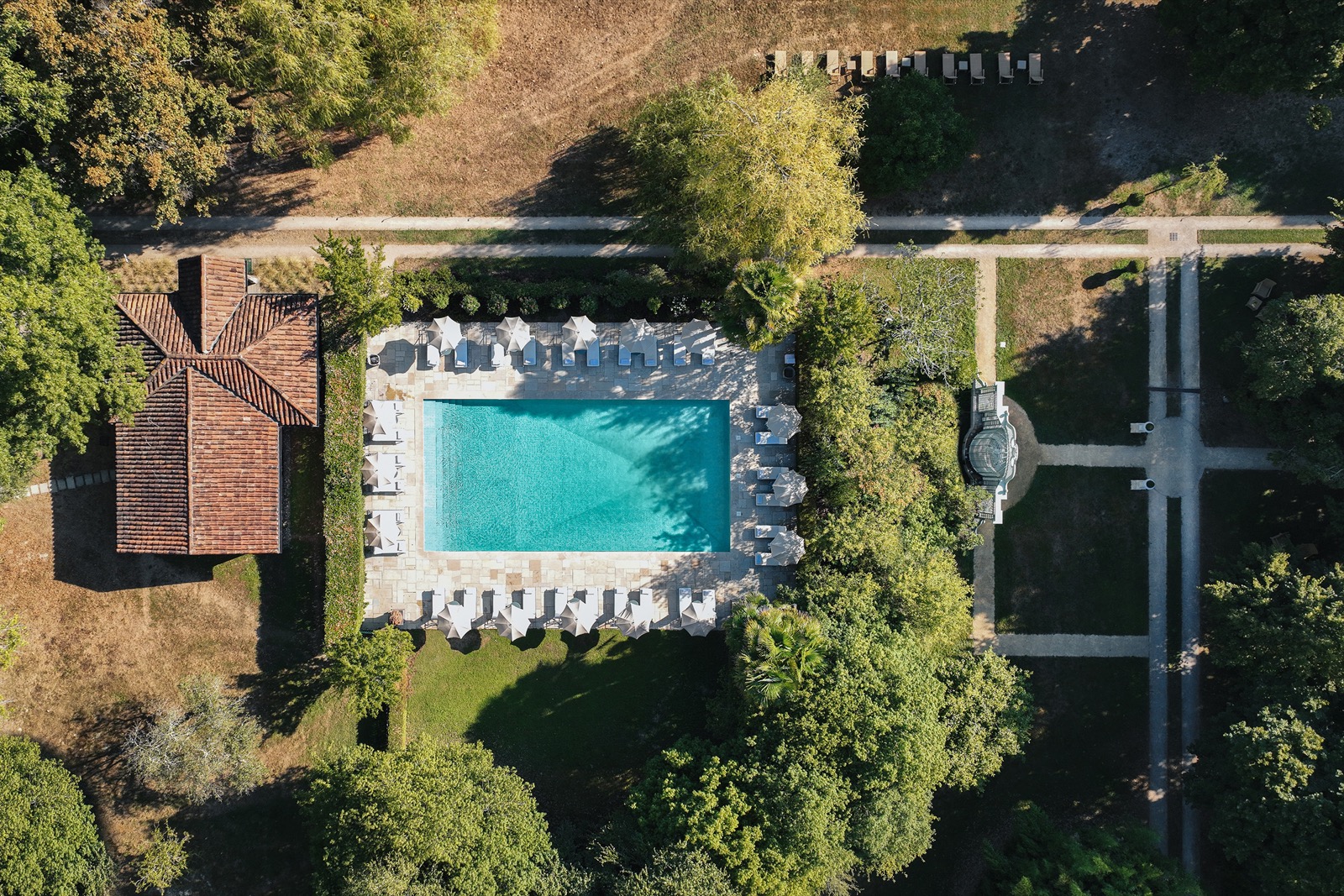 La piscine des Prés d'Eugénie vue du ciel, entourée de parasols et du parc landais