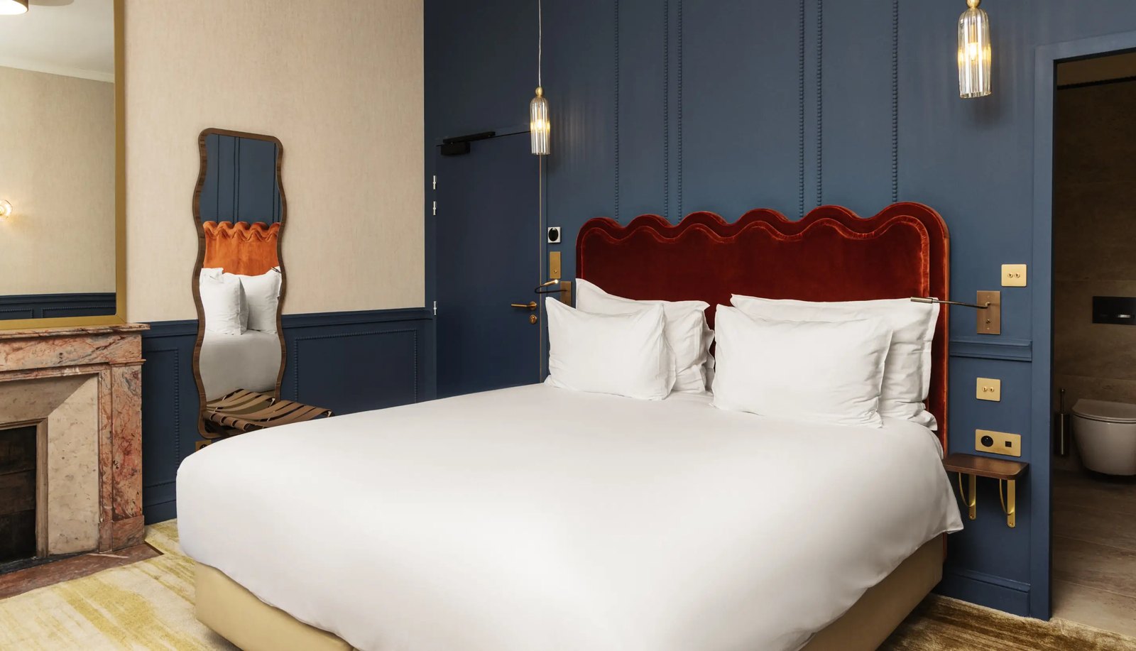 Chambre Deluxe du Château du Portereau, boiseries bleu nuit et tête de lit en velours rouge
