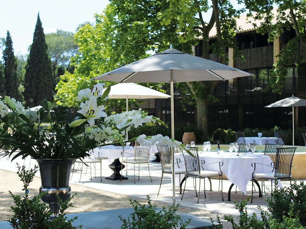 La terrasse du Domaine de Manville, ses parasols et ses cyprès