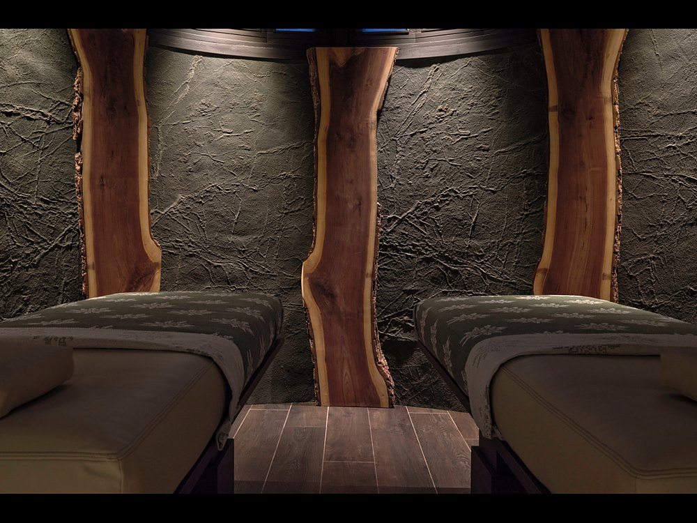 Les lits de repos du spa du Lodge Park à Megève, contre un mur de pierre brute