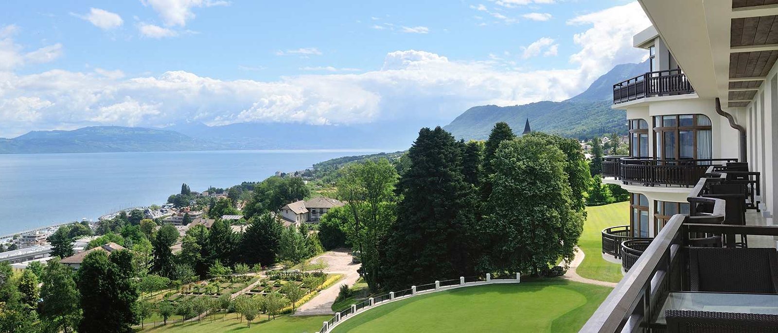 Le parc de l'Hôtel Royal vu depuis le balcon d'une suite, ses pelouses et ses arbres, Évian-les-Bains et le lac Léman jusqu'aux montagnes