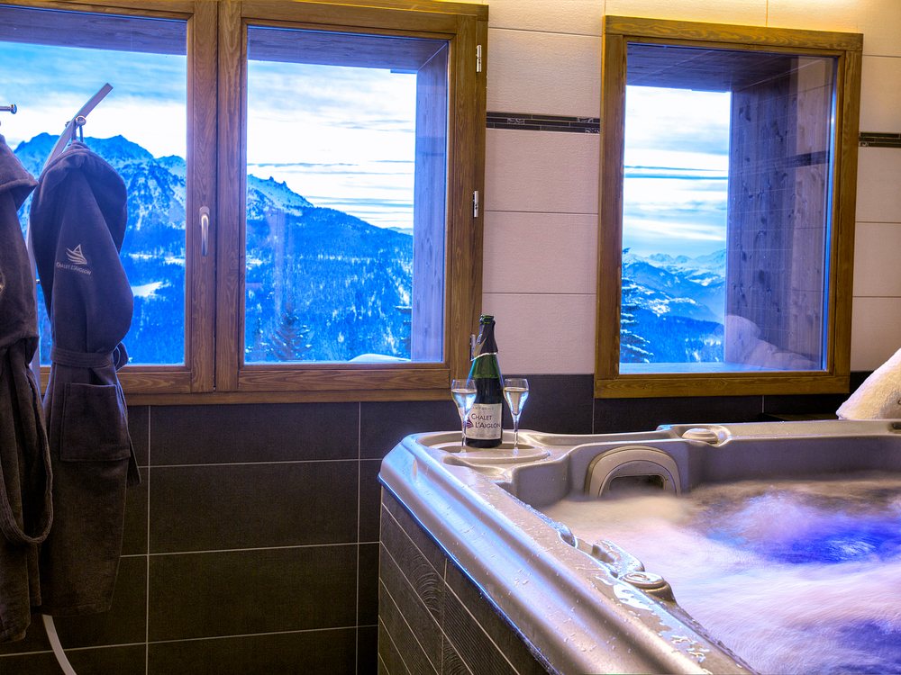Le jacuzzi intérieur du Chalet l'Aiglon, devant deux fenêtres ouvertes sur les sommets de la Tarentaise