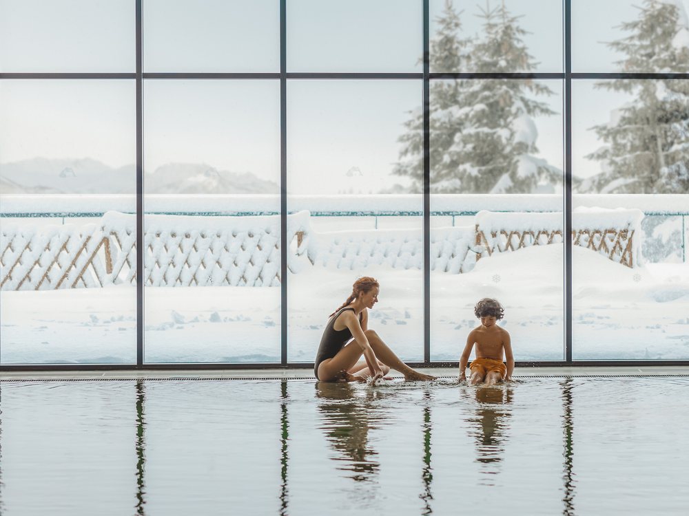 Une mère et son enfant dans la piscine intérieure du Club Med La Rosière, devant une baie ouverte sur la neige