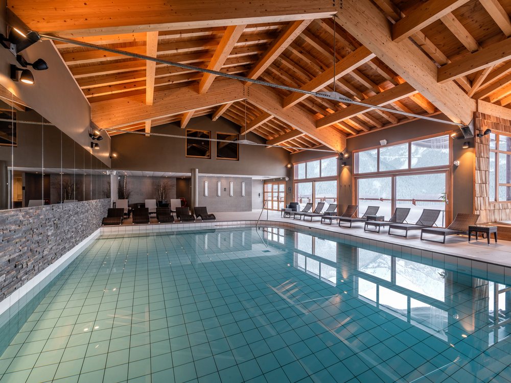 La piscine intérieure du Spa Nuxe d'I.L.Y Hotels La Rosière, sous une charpente de bois et de grandes baies