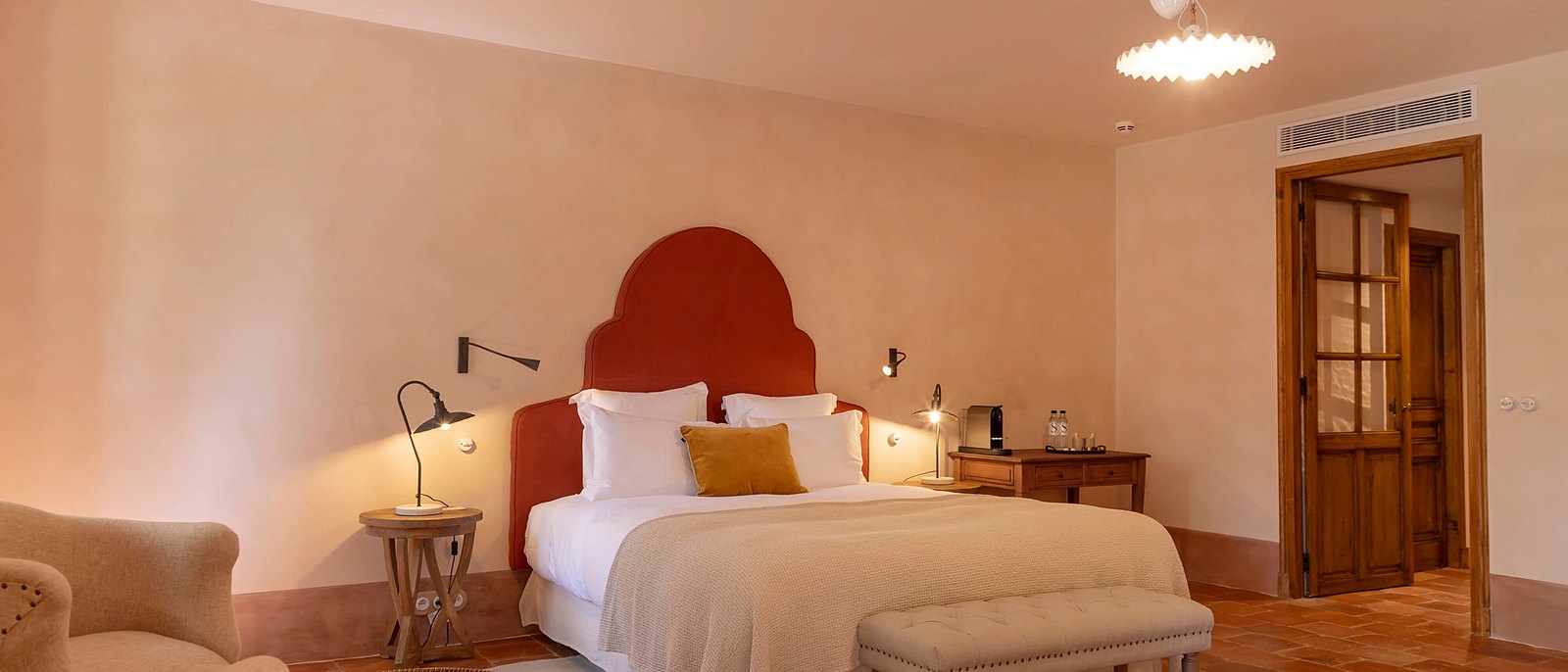 Une chambre du Hameau de Saparale, tête de lit cintrée et sol en tomettes