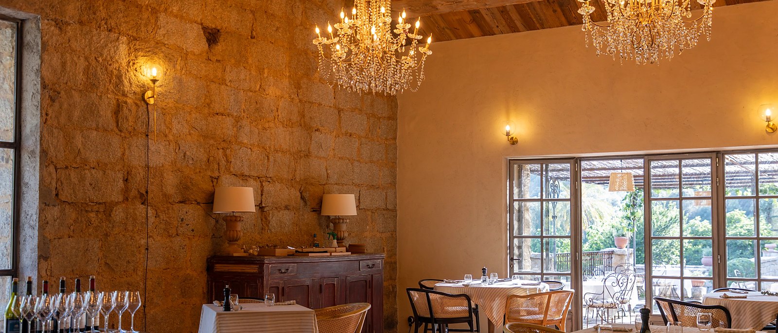 La salle du restaurant Sopravigna, ses lustres et son mur de pierre, dans l'ancien chai du Hameau de Saparale