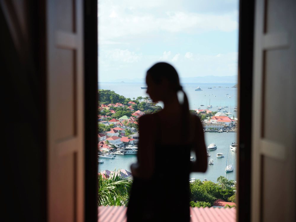 La silhouette d'une cliente à la fenêtre d'une suite du Fouquet's Saint-Barth, face au port de Gustavia