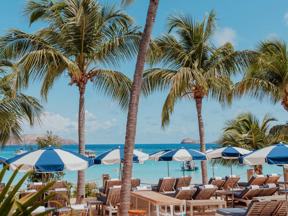 Le Gyp Sea Beach Club sur la baie de Saint-Jean, ses parasols rayés bleu et blanc sous les cocotiers