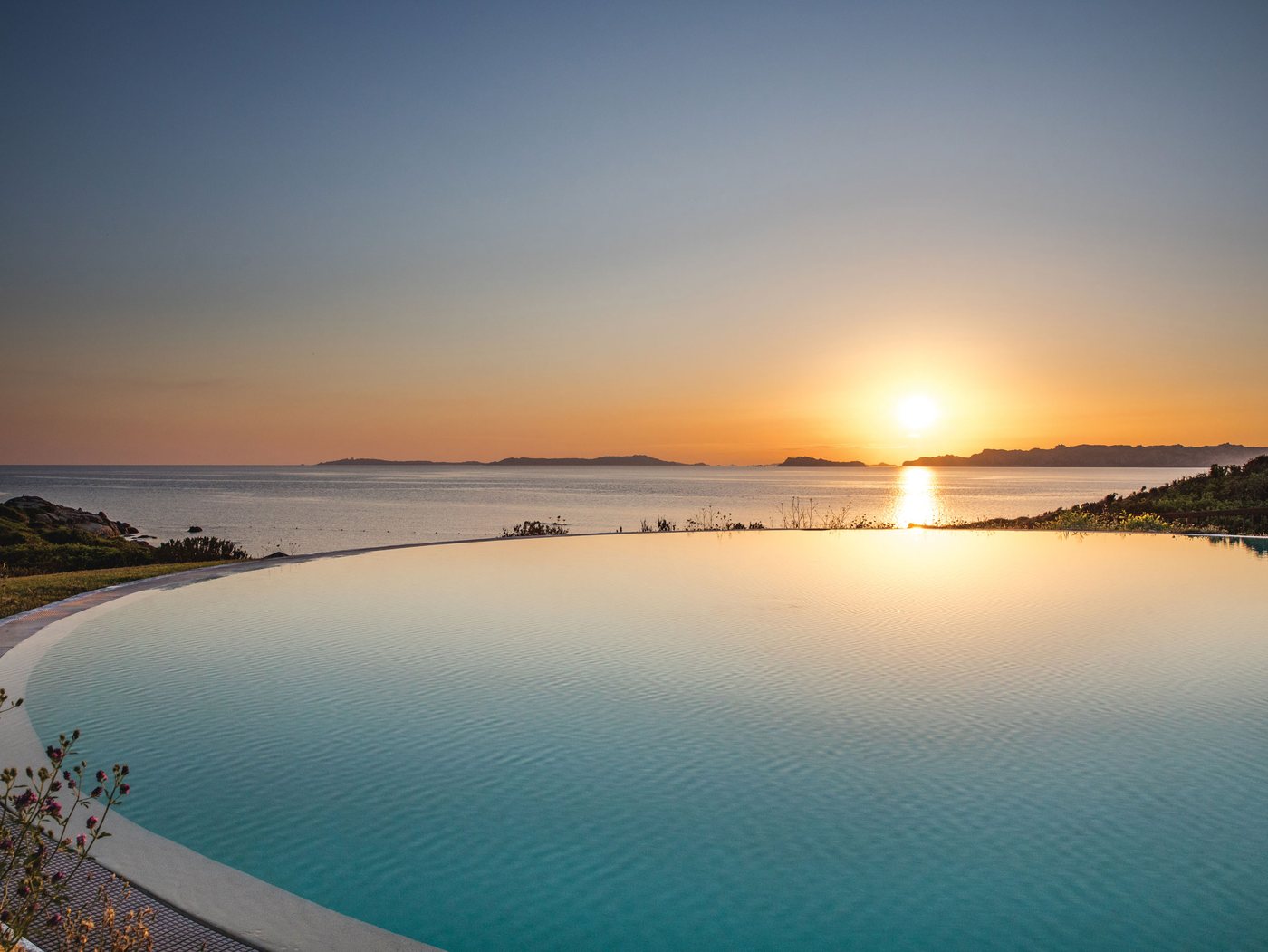 La piscine à débordement du Resort Valle dell'Erica au coucher du soleil, face à l'archipel de La Maddalena