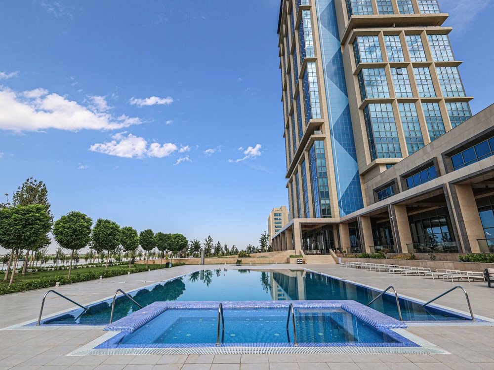 La piscine extérieure du Hilton Samarkand Regency, au pied de sa tour de verre, dans le complexe Silk Road Samarkand