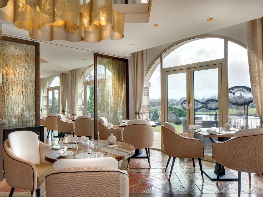 La salle du restaurant deux étoiles de La Côte Saint-Jacques, tables dressées et baies cintrées sur le jardin