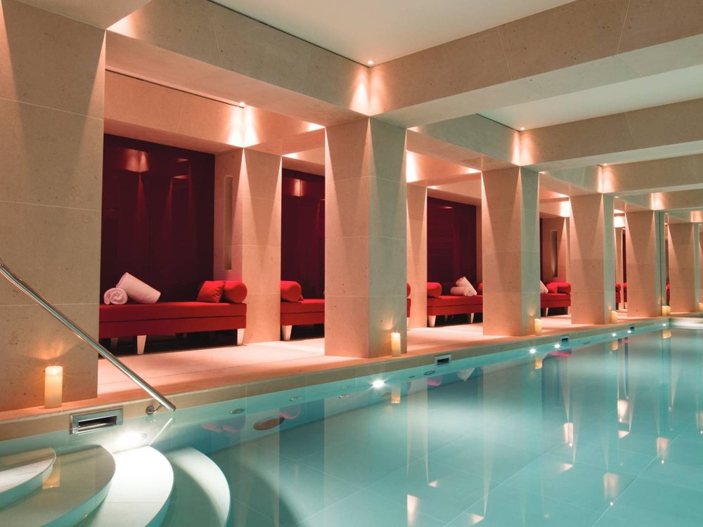 La piscine du Spa Nescens de La Réserve Paris, piliers de pierre et alcôves rouges éclairées