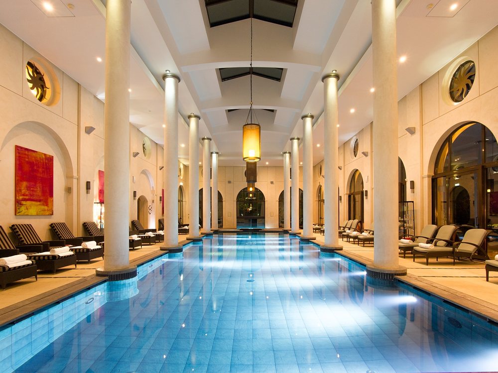 La piscine intérieure du spa de Terre Blanche, colonnades blanches, bassin bleu et transats alignés