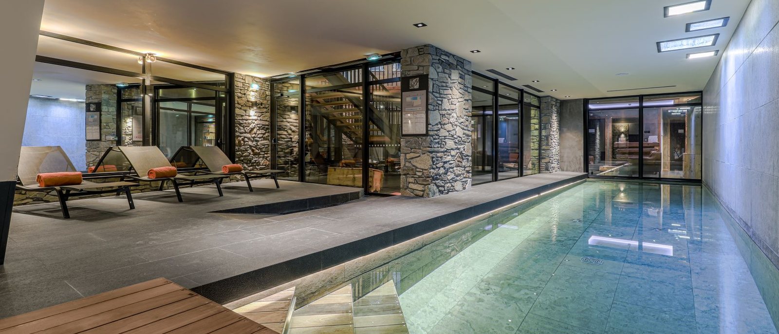 Le couloir de nage à contre-courant du spa du M de Megève, ses transats et ses murs de pierre