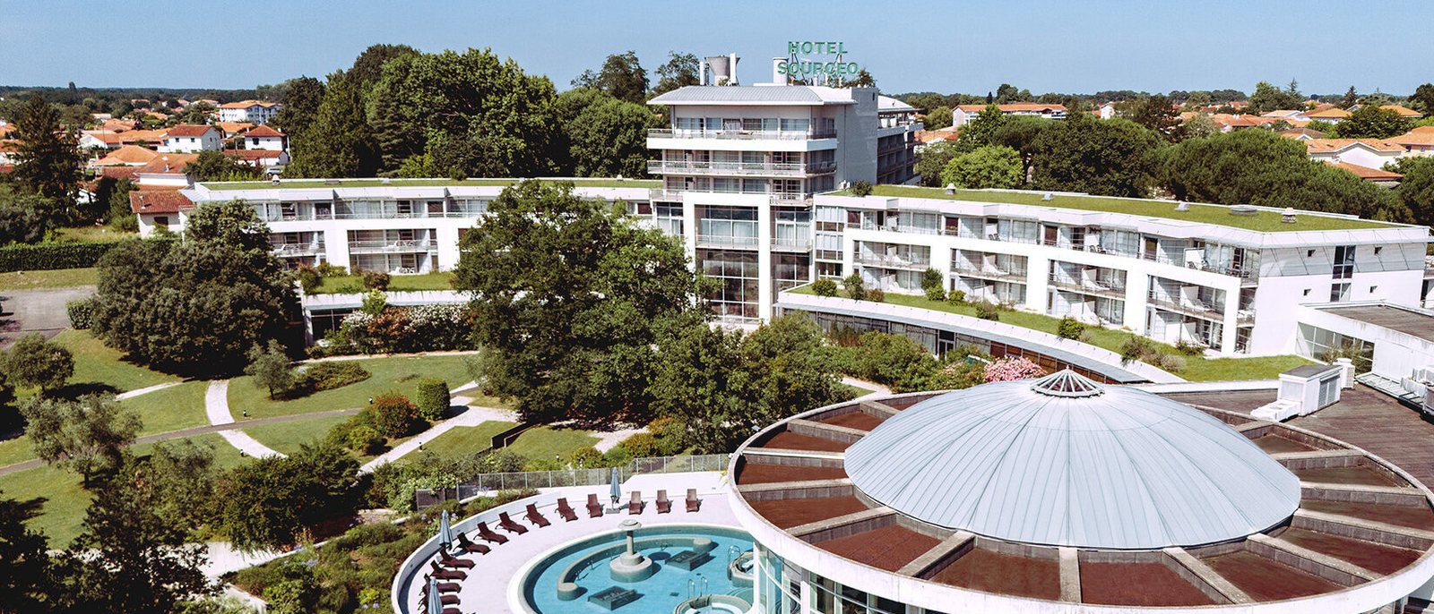 Le complexe des Thermes Adour à Saint-Paul-lès-Dax vu du ciel, ses bâtiments blancs et la coupole de Sourcéo