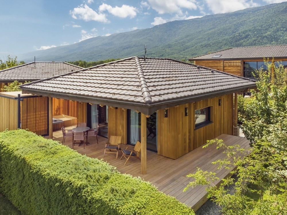 Un Lodge Jacuzzi de Jiva Hill, bungalow de bois et sa terrasse, au pied des montagnes du Jura