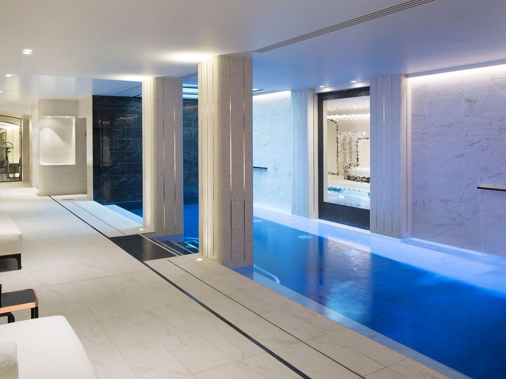 La piscine du spa du Narcisse Blanc à Paris, bassin bleu entre des colonnes de pierre claire