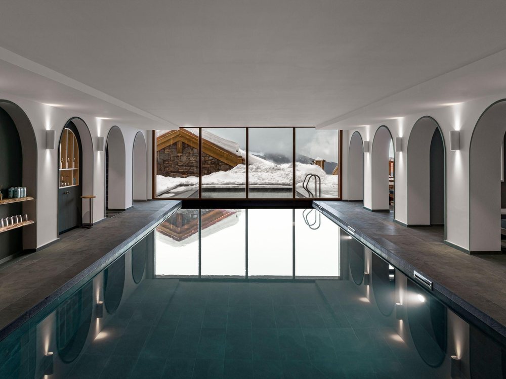 Les deux piscines du spa du Coucou, intérieure et extérieure, séparées par une baie vitrée ouverte sur la neige