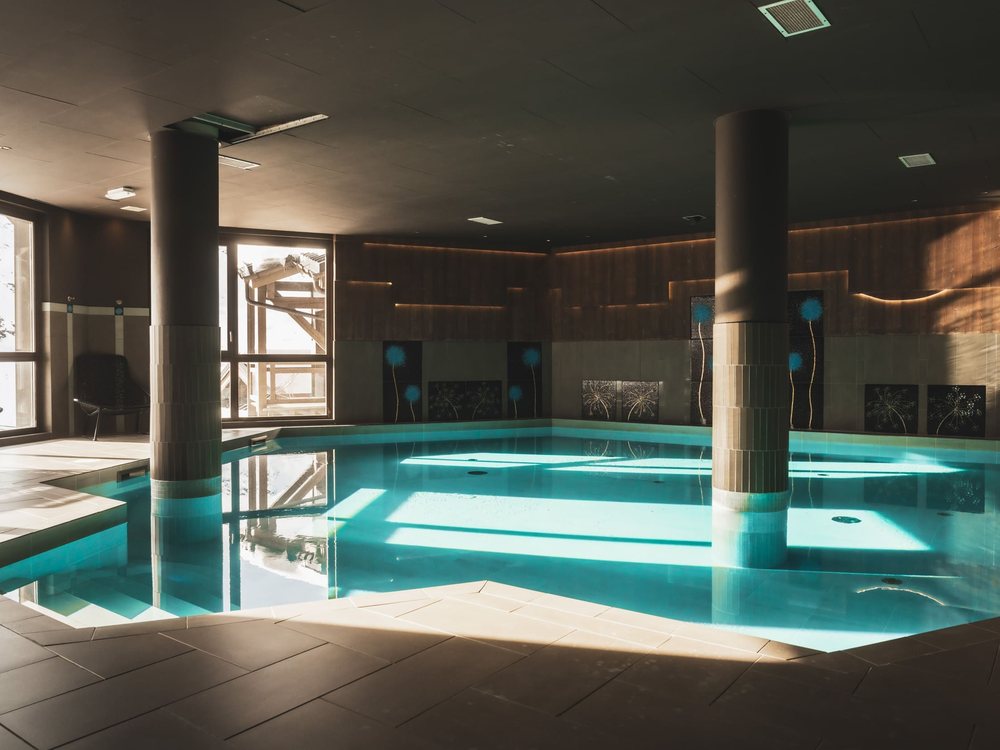La piscine intérieure chauffée du Hameau du Kashmir, ses colonnes et ses boiseries sous une lumière dorée