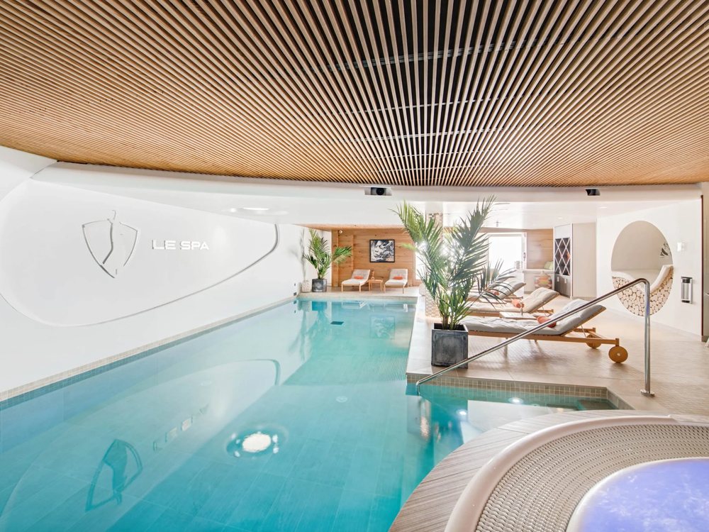 La piscine intérieure du spa du Pashmina, son plafond de lattes de bois et son jacuzzi au premier plan
