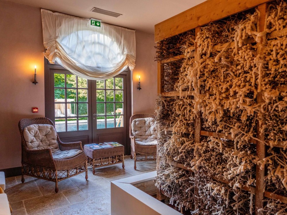 L'espace d'halothérapie du Château Louise de La Vallière, mur de sel cristallisé, fauteuils de rotin et vue sur la piscine