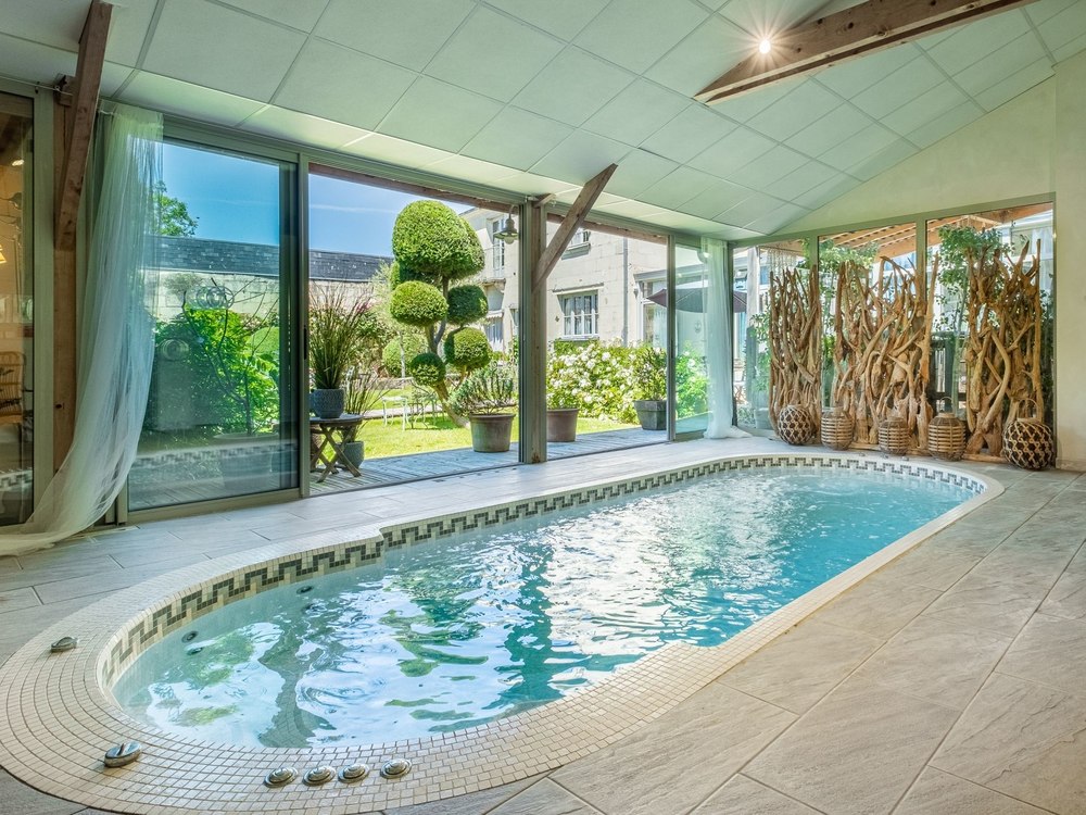 La piscine intérieure du spa Le Sent Bon à La Marine de Loire, baies ouvertes sur le jardin et paravent de bois flotté