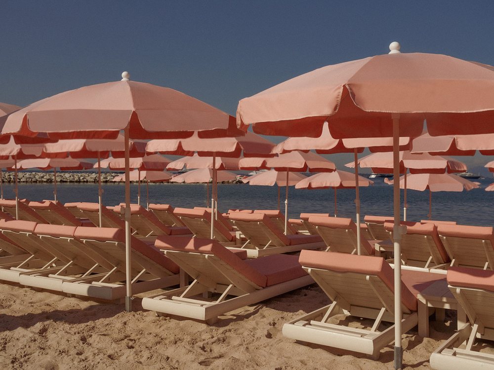 Les parasols et transats roses de la plage privée du Cap d'Antibes Beach Hotel, au bord de la Méditerranée