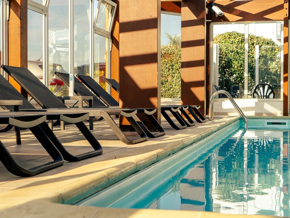 La piscine couverte des Dunes, ses transats noirs et ses baies vitrées, à La Tranche-sur-Mer