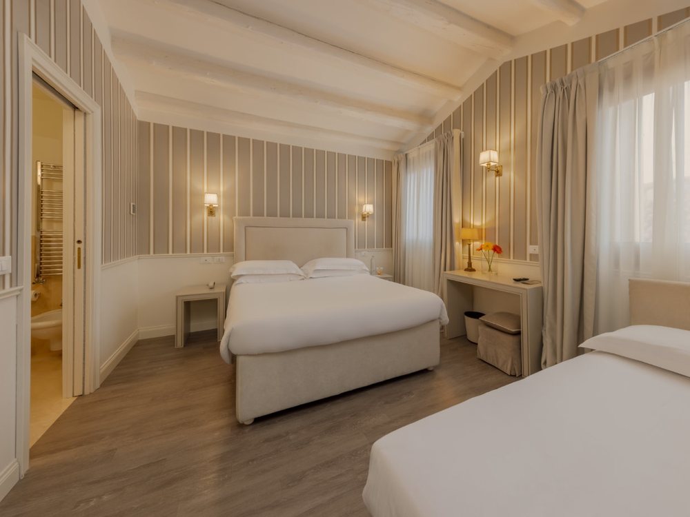 Une chambre claire de l'Hotel Bartolomeo, ses deux lits blancs, ses rideaux et son plafond mansardé