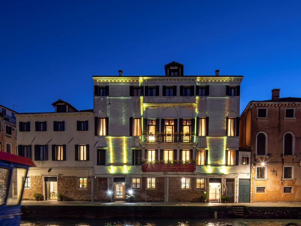 La façade de Ca' Bonfadini illuminée à la tombée de la nuit, au bord du canal de Cannaregio