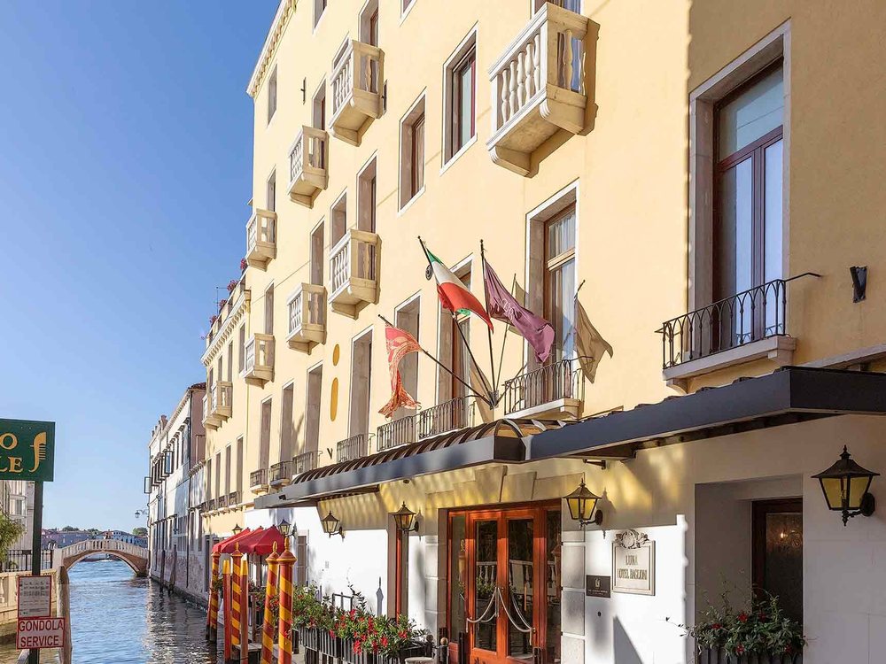 La façade claire du Baglioni Hotel Luna, ses drapeaux et ses balcons au bord du canal, à deux pas de Saint-Marc
