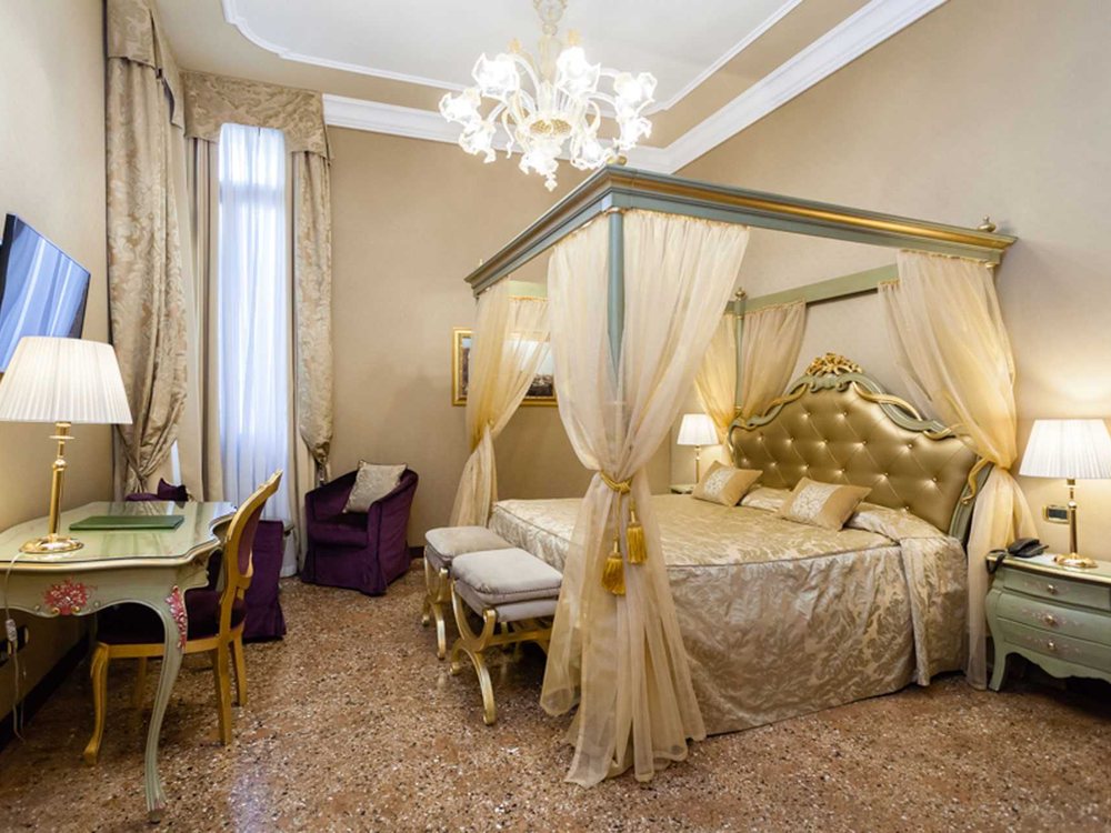 Une junior suite d'Al Ponte Mocenigo, son lit à baldaquin, son lustre de Murano et ses tissus damassés