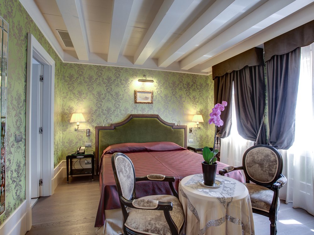 Une chambre de l'Hotel Moresco, son lit aux tons roses, sa table ronde et ses tentures vertes