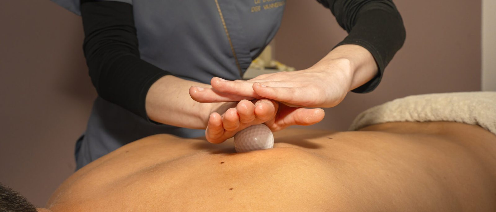 Les mains d'une praticienne posées sur le dos d'une cliente pendant un massage au spa du Domaine des Vanneaux