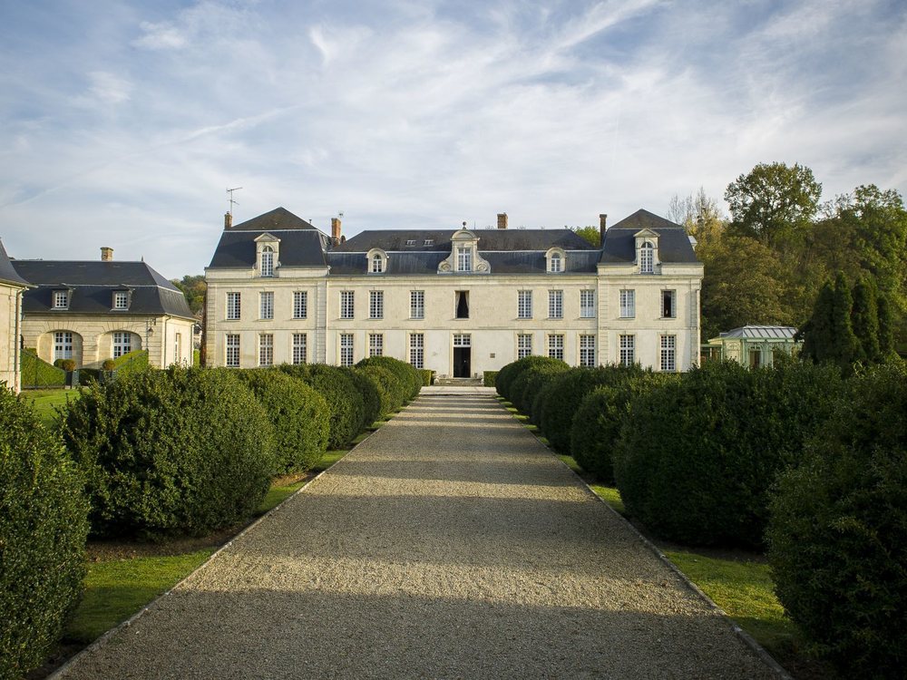 L'allée bordée de buis taillés qui mène à la façade classique du Château de Courcelles